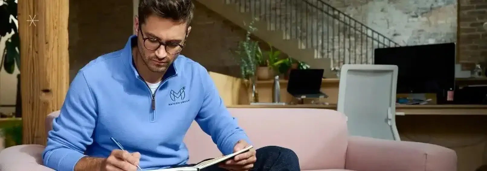 Professional employee wearing a branded quarter-zip sweatshirt in a modern office environment